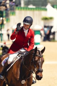 Person in read coat for showjumping on a horse